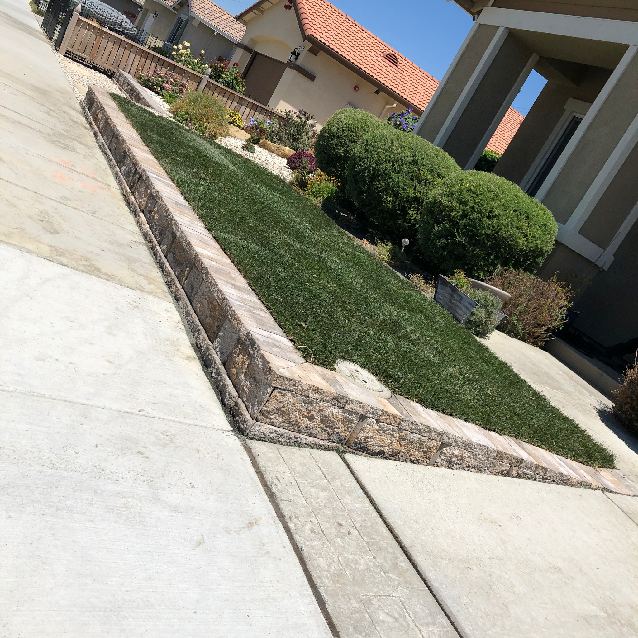 Artificial turf front yard with a stone retaining edge installed by A&F Landscaping